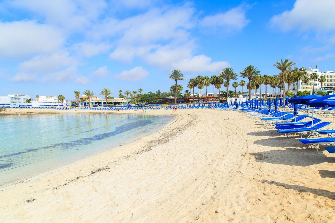 'Blue beach umbrellas and sunbeds on Sandy Beach in Ayia Napa, Cyprus' - кипр